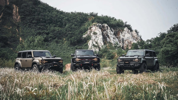 Premium Ford Bronco upgraded with TAMER4X4 dry carbon fiber exterior parts driving on an off-road trail.